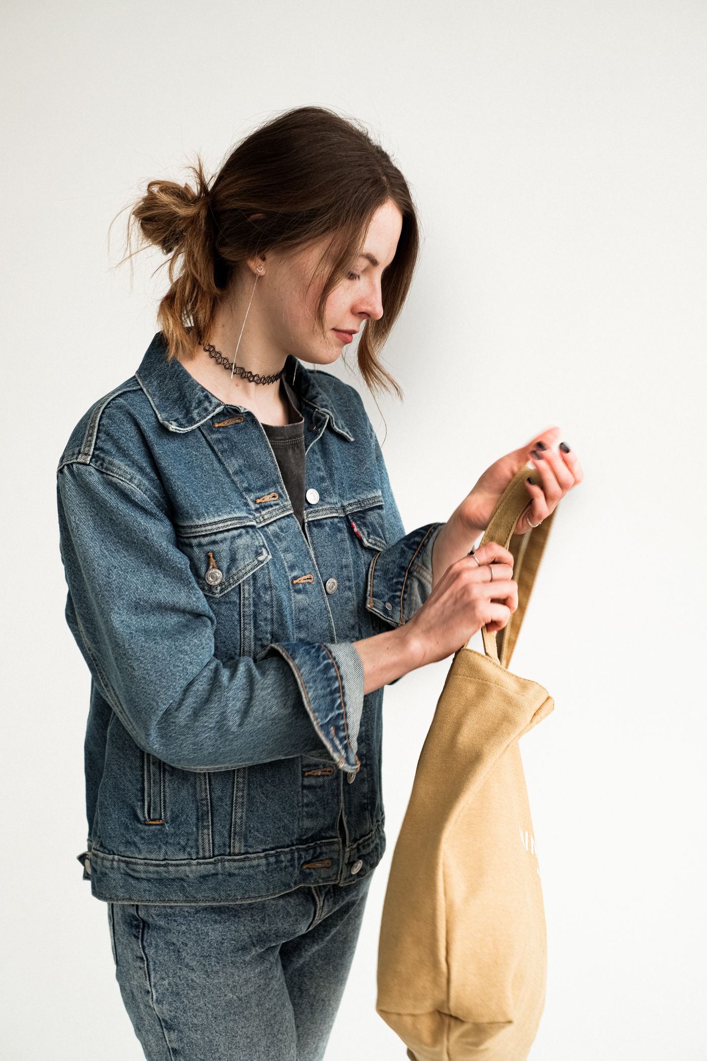 A woman checking the contents of a canvas tote bag.