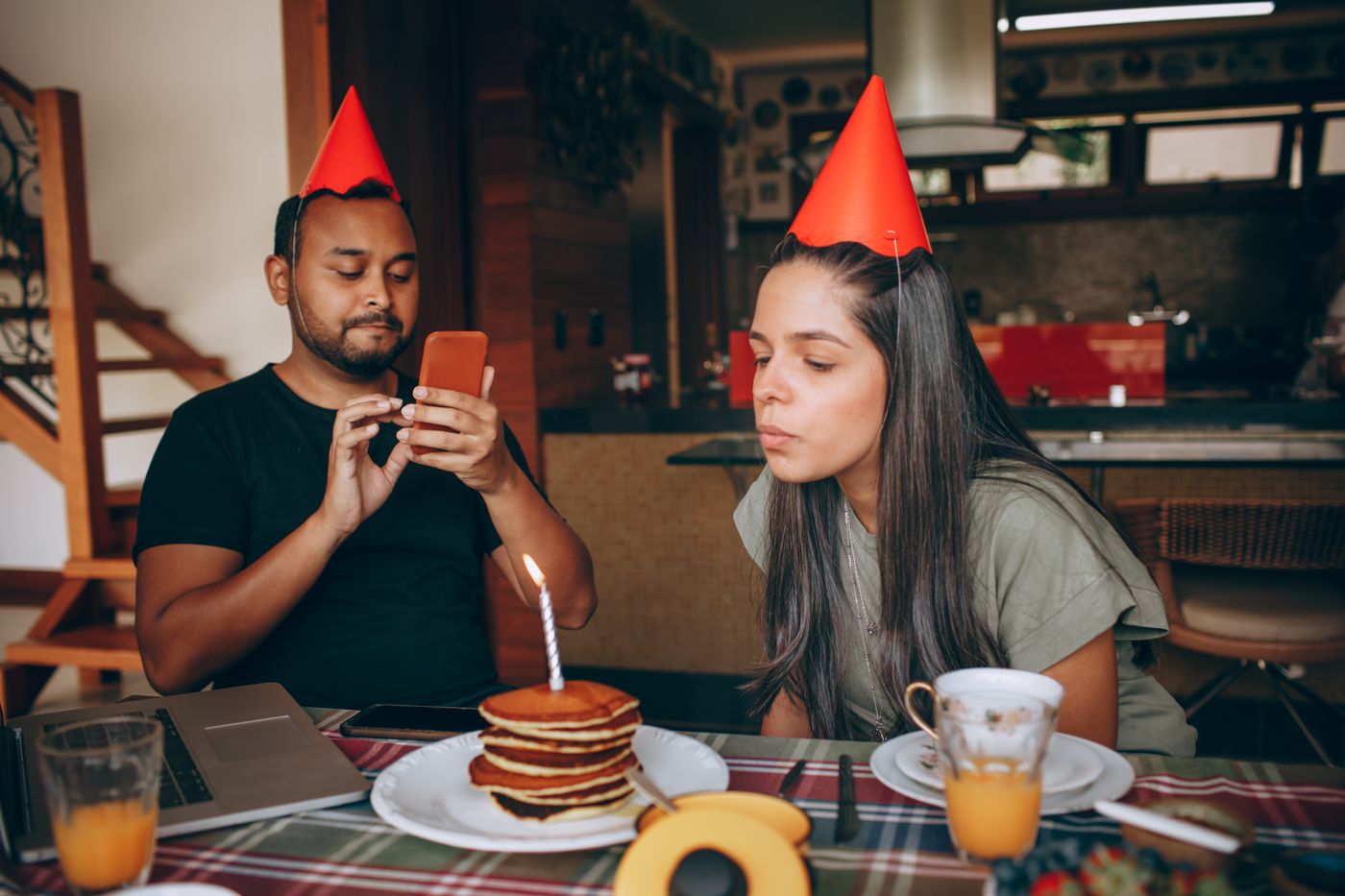 Birthday pancakes with a candle, coffee and juice at a breakfast table.