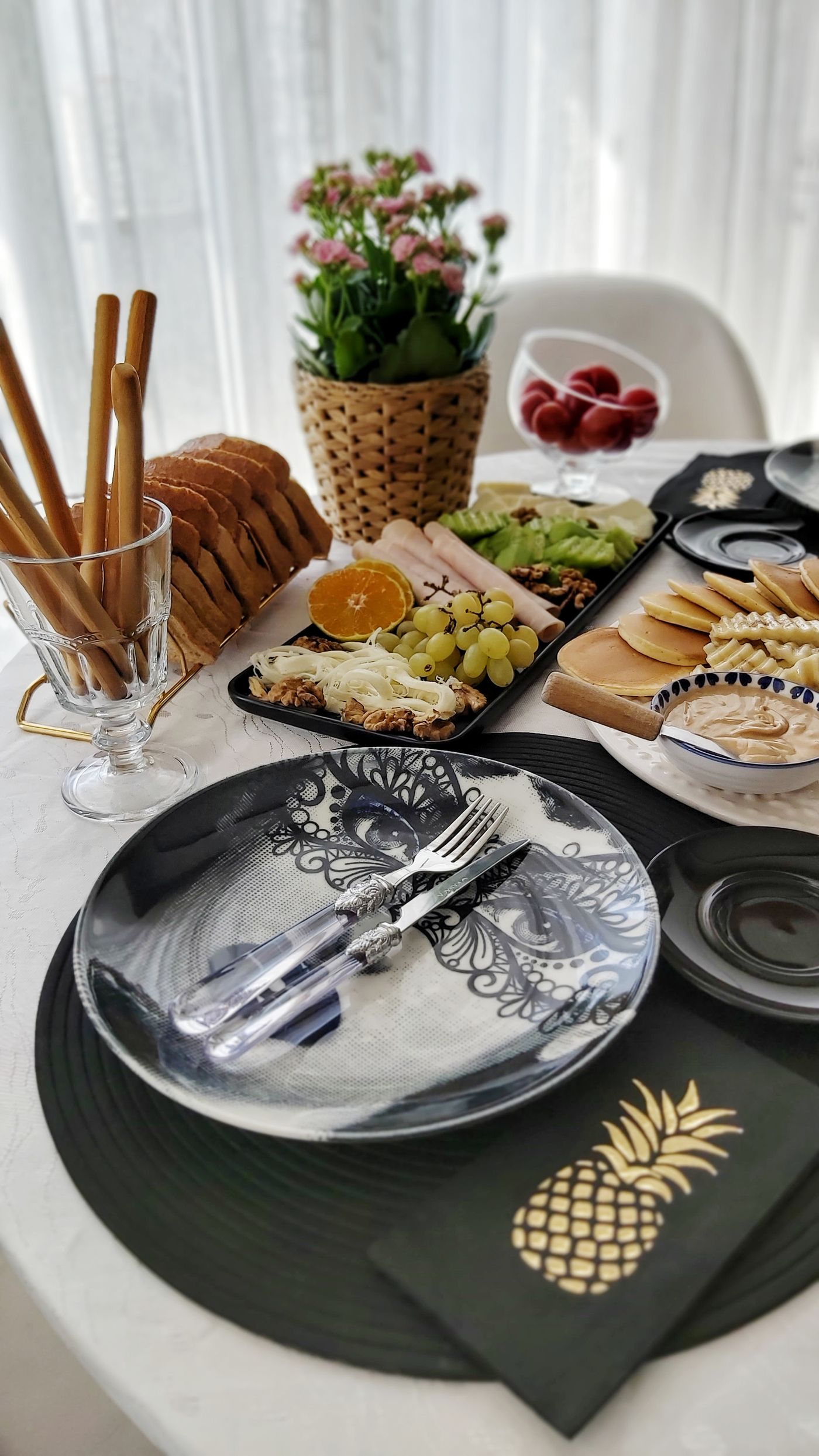 A breakfast table with plates, fruit, bread and serving boards.