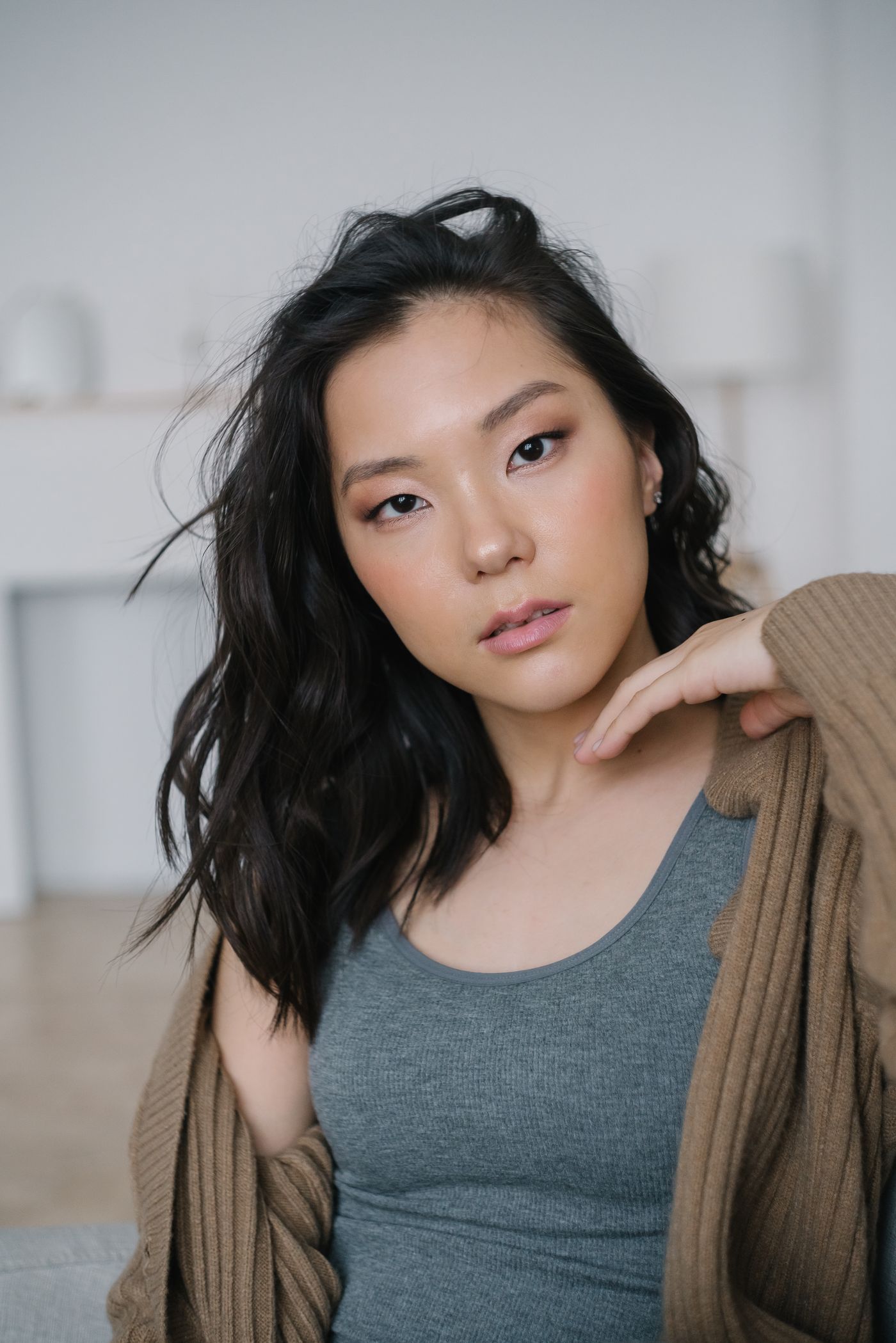 A woman wearing a brown ribbed cardigan over a grey tank top.