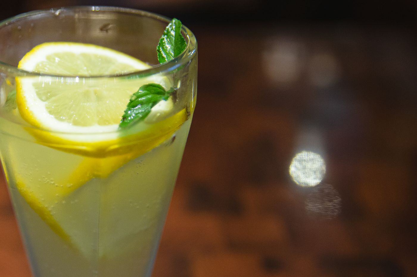 A glass of lemon drink garnished with lemon slices and mint.