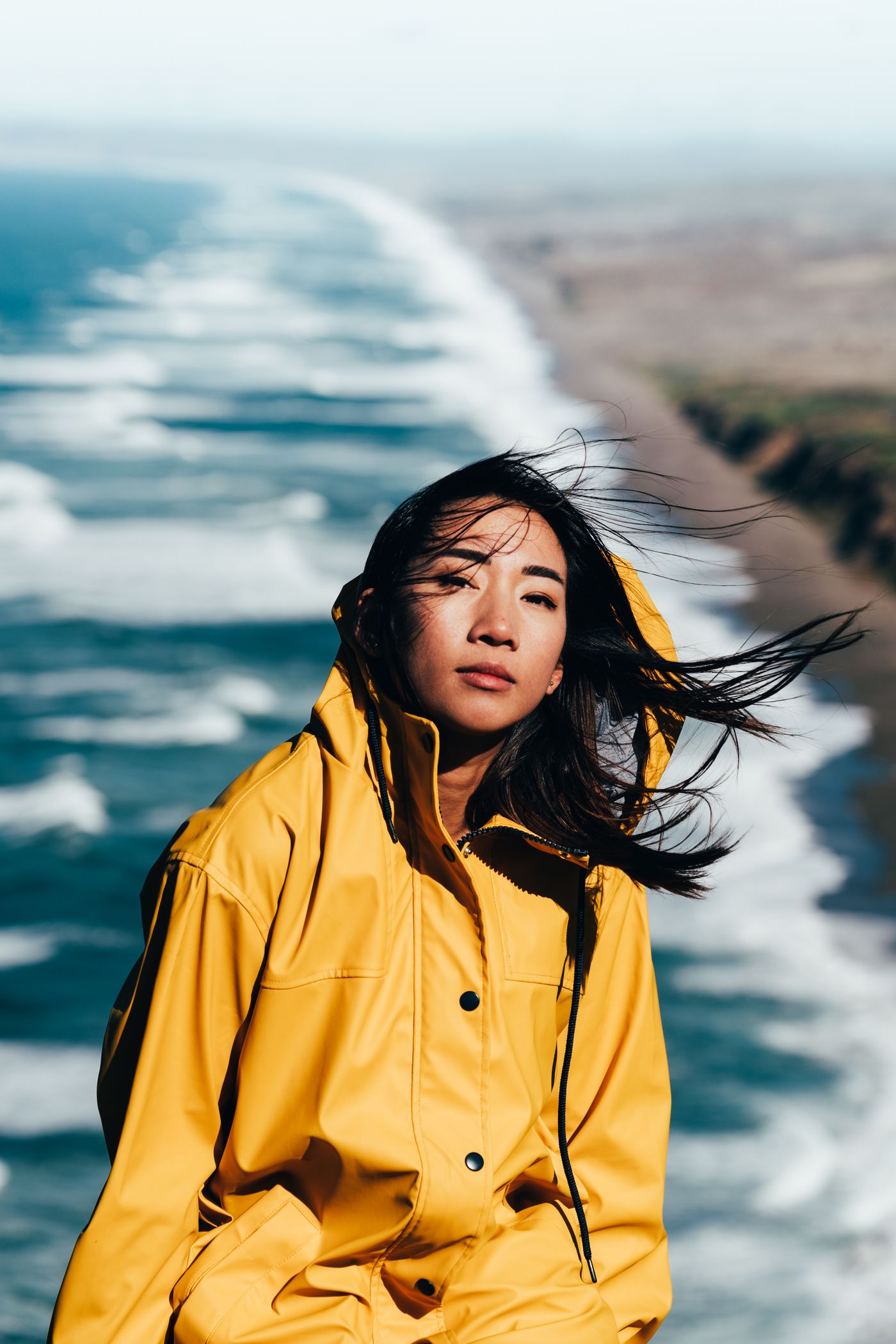 A woman wearing a yellow raincoat beside the coast.