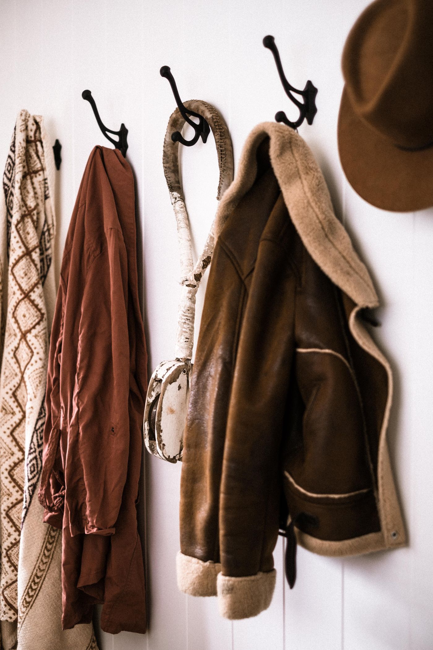 Outerwear, a scarf and a hat hanging from wall hooks.