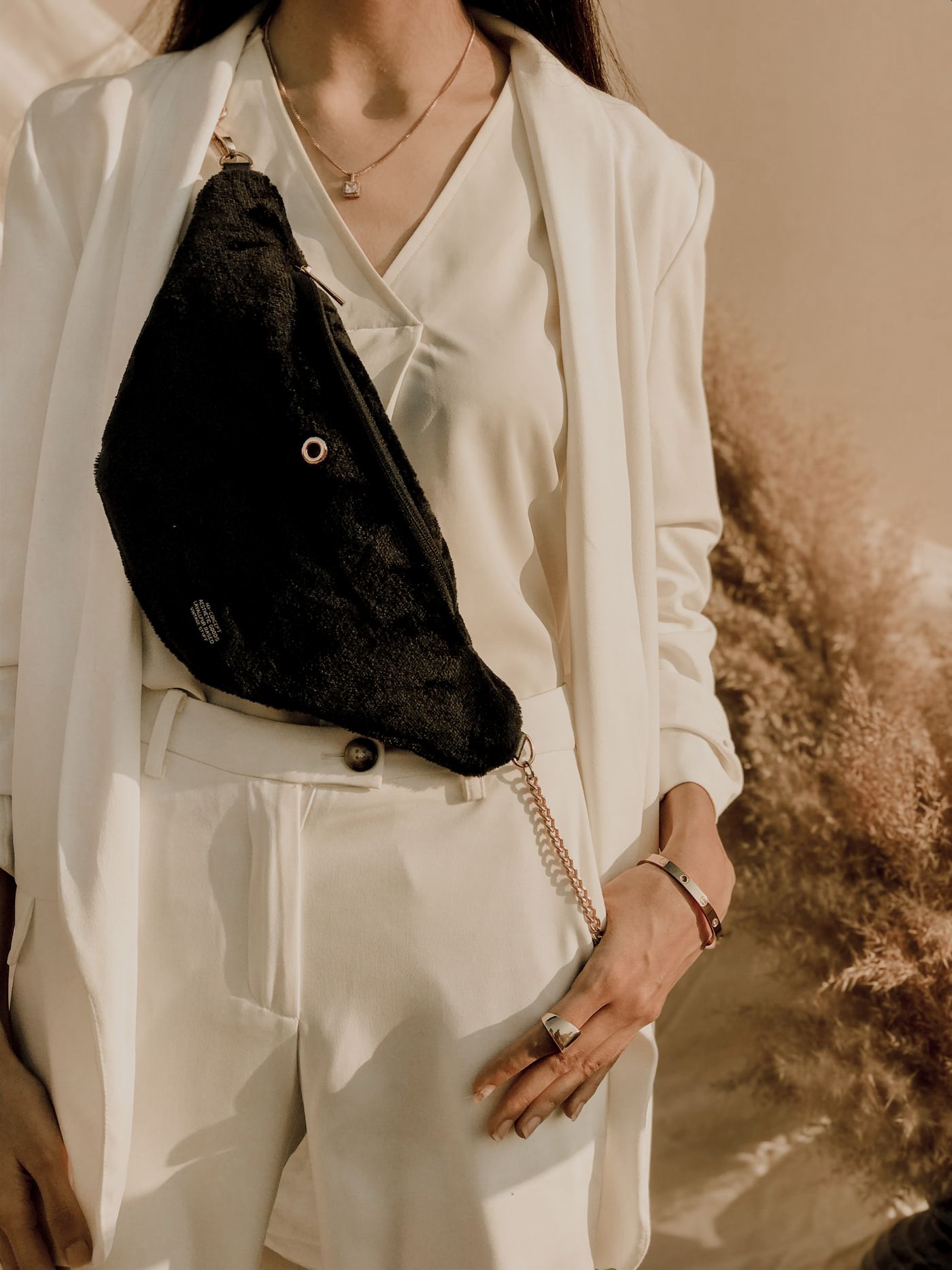 A black crossbody bag worn over a light outfit.