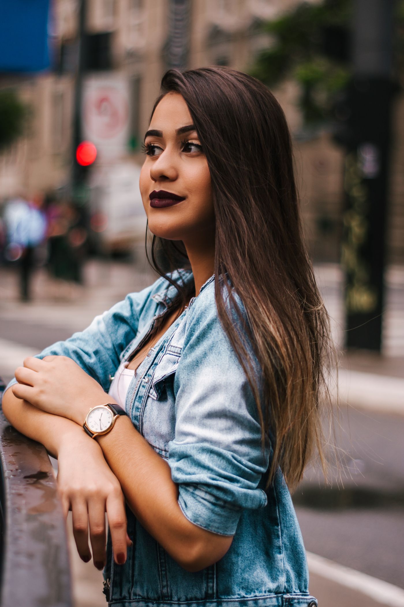 A woman wearing a blue denim jacket on a city street.