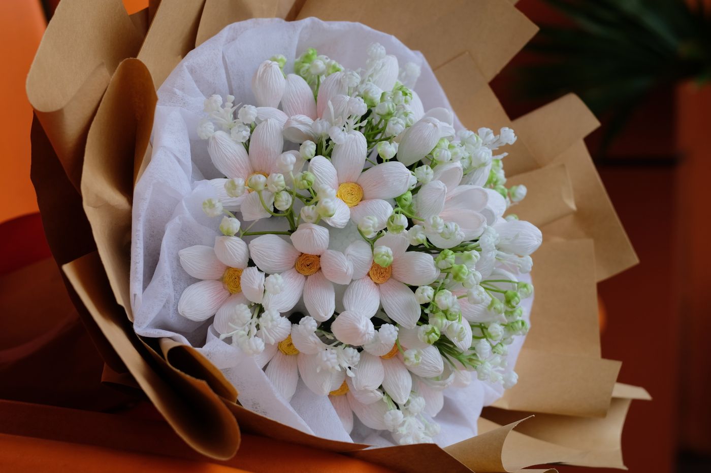 A bouquet of white flowers wrapped in brown paper.