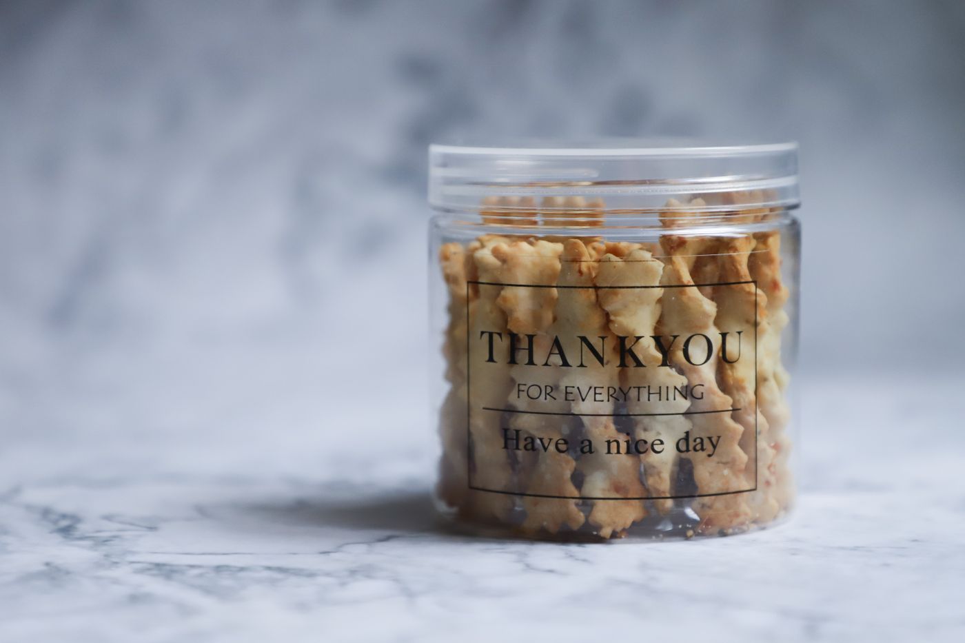 A clear jar of cookies with a thank-you label.
