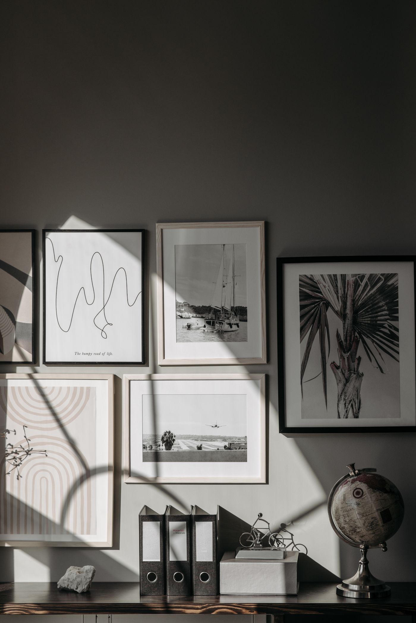A group of framed prints arranged above a console.