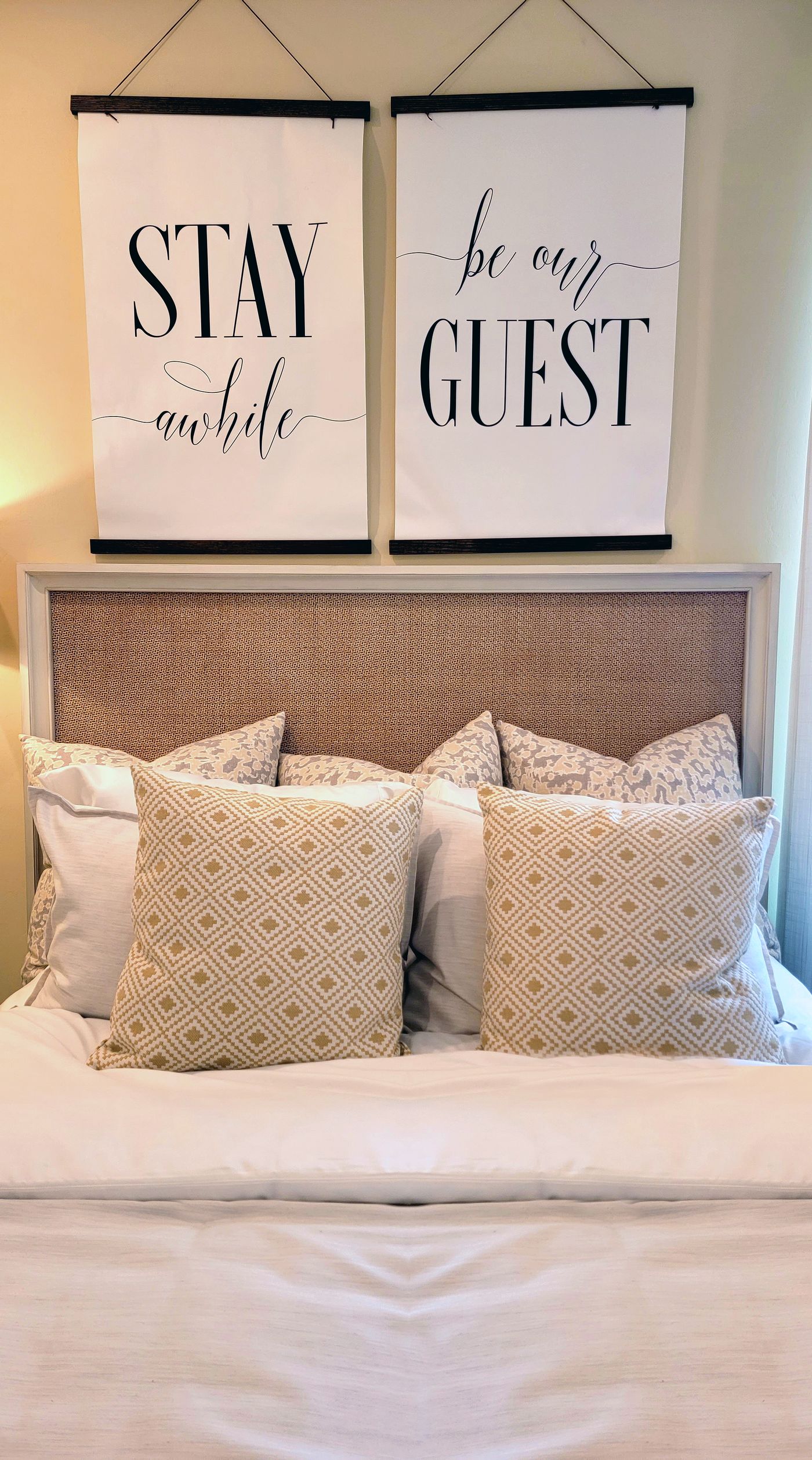 A made-up guest bed with pillows and a woven headboard.