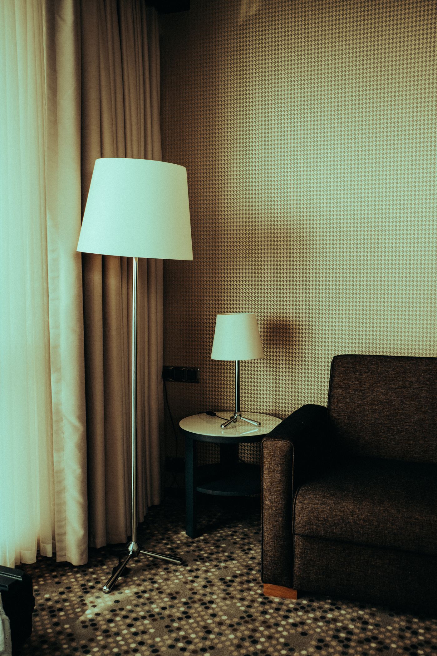 A reading chair lit by a floor lamp and a smaller table lamp.