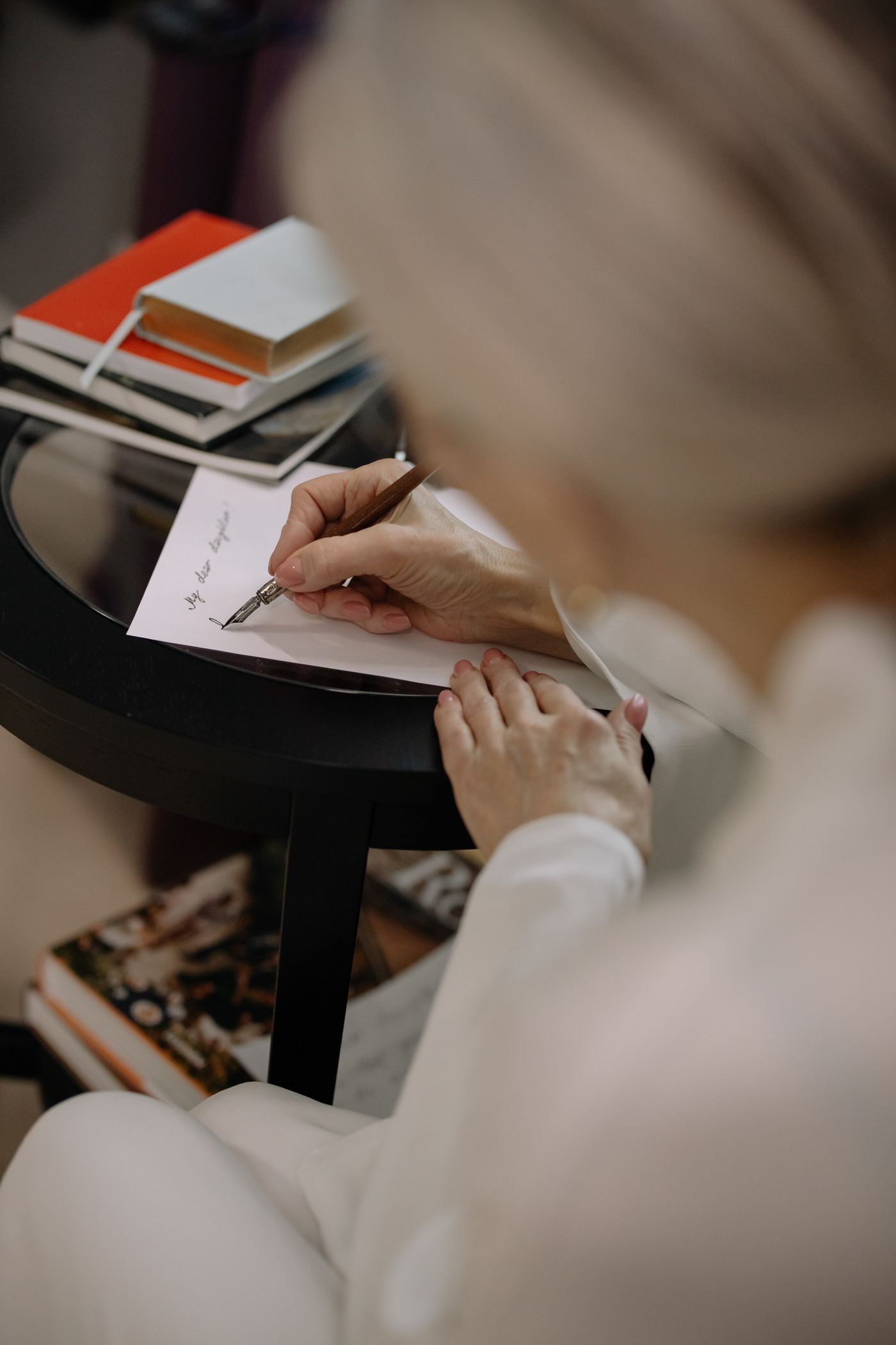 A person writing a handwritten note beside a stack of books.