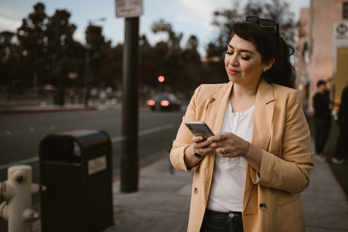 A beige blazer worn over a plain white top on a city street.