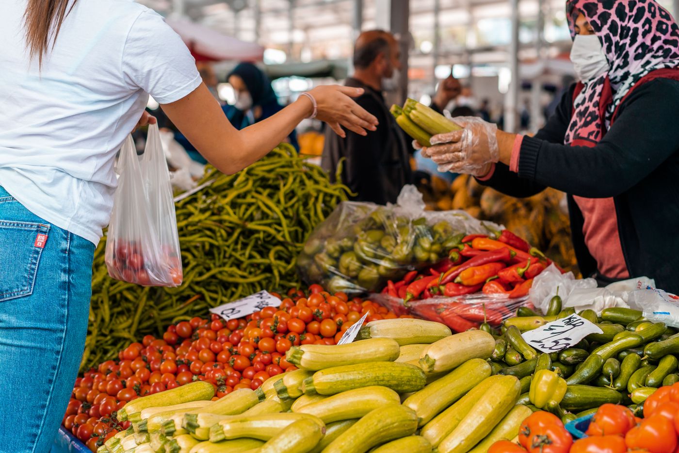 A customer buying fresh vegetables at a market stall.