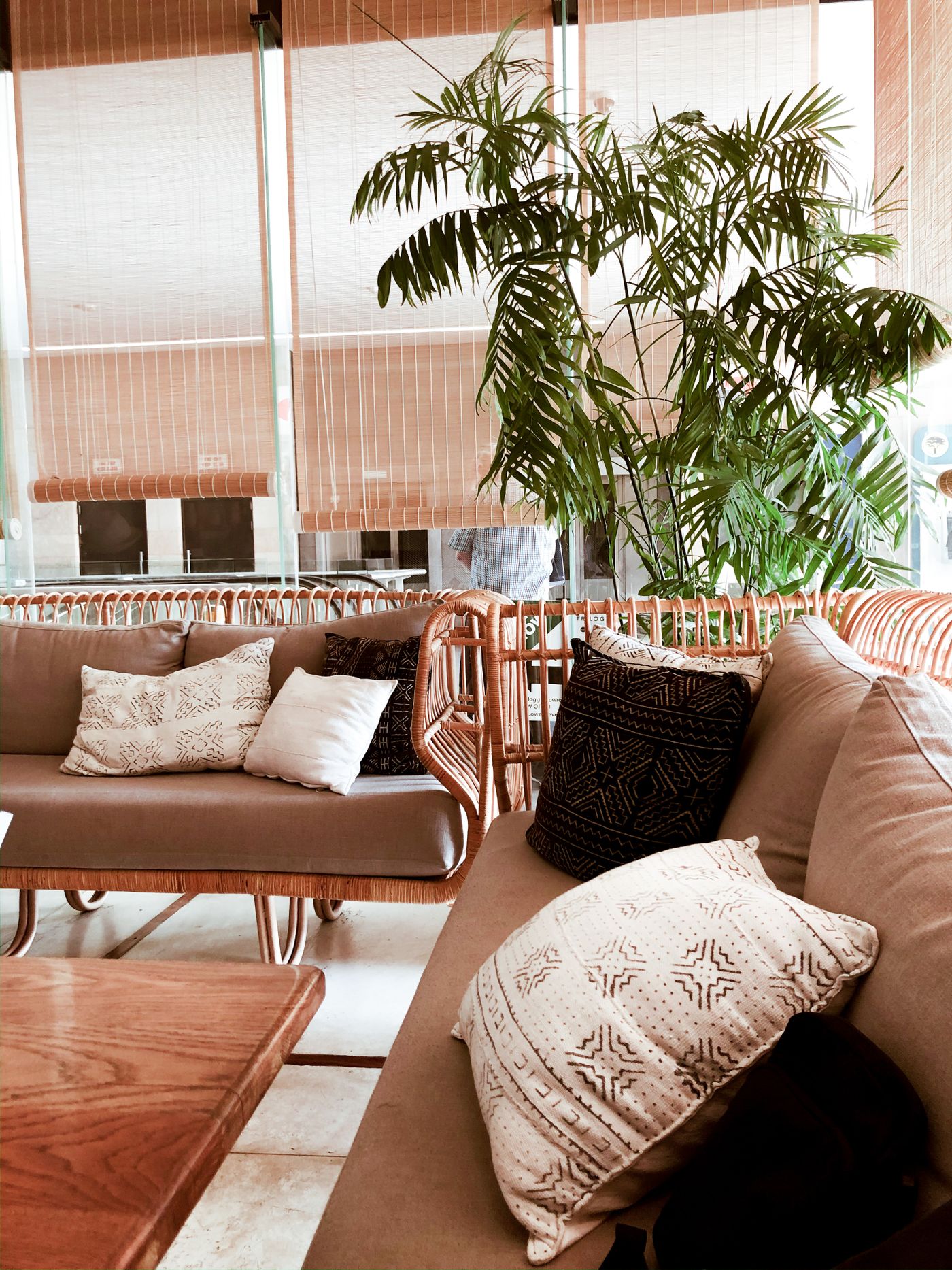 Rattan furniture, textured cushions and woven blinds in a neutral room.