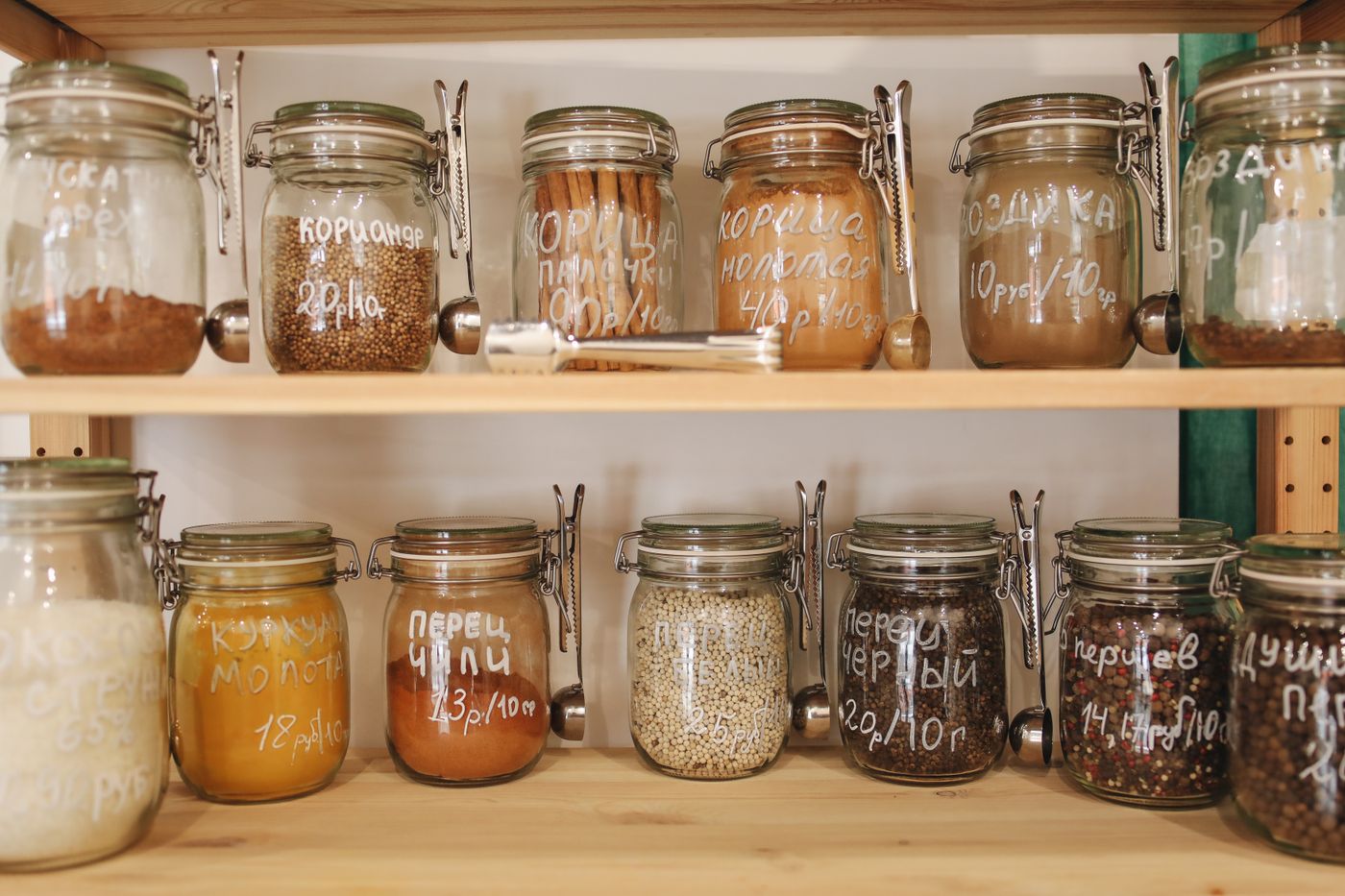 Glass jars of dry pantry ingredients arranged on wooden shelves.