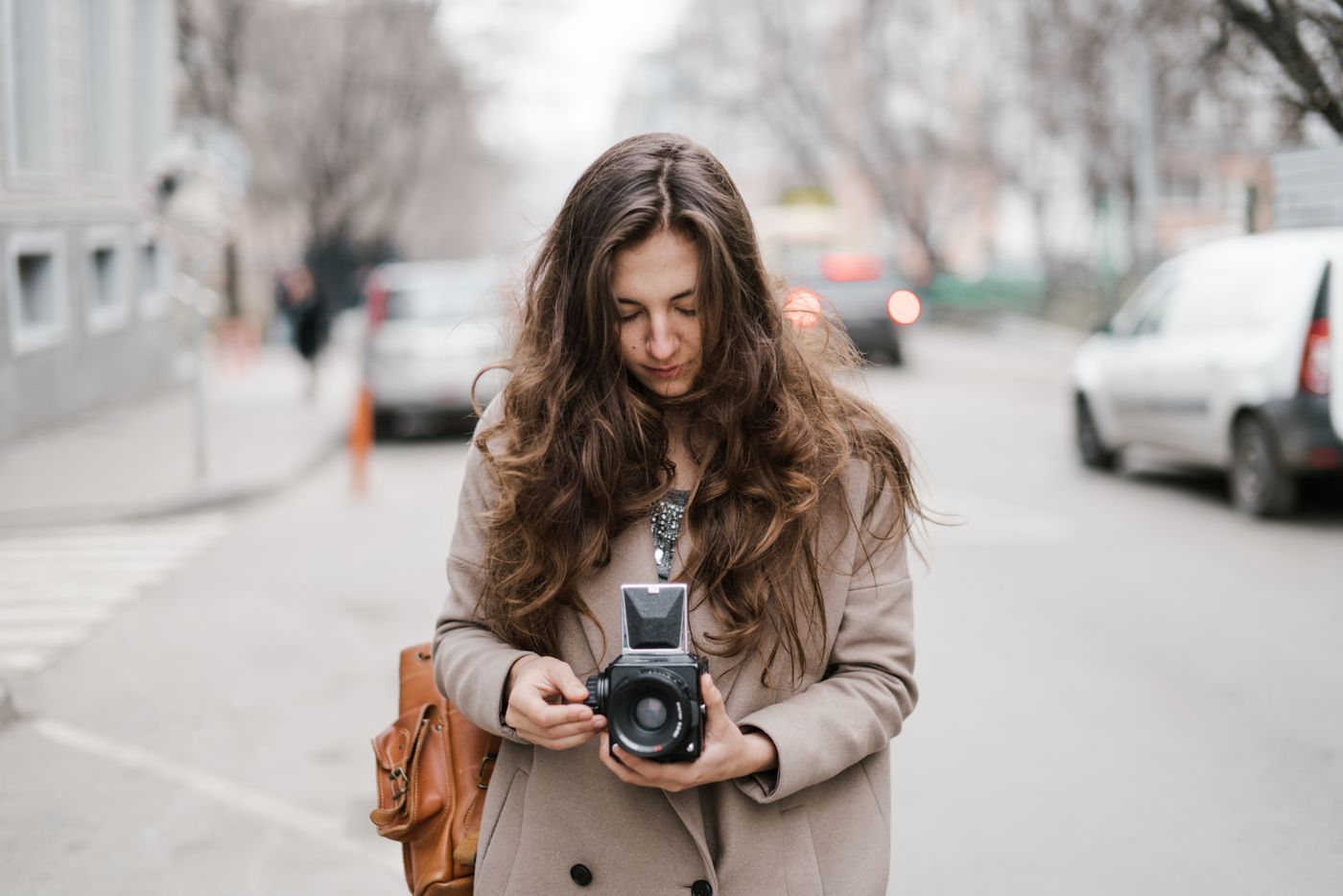 A woman checking a camera during a walk in the city.