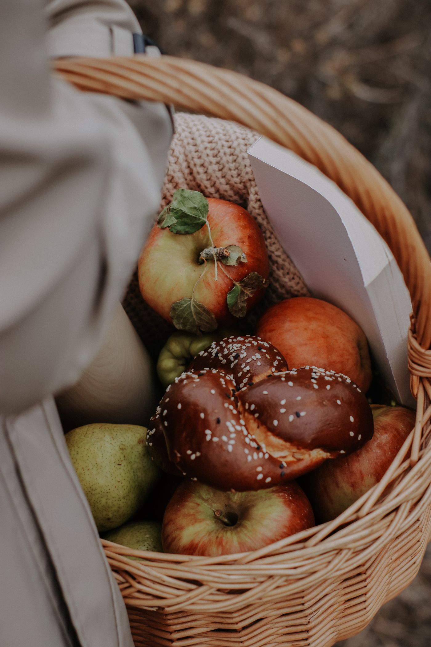 A wicker picnic basket packed with fruit and bread.