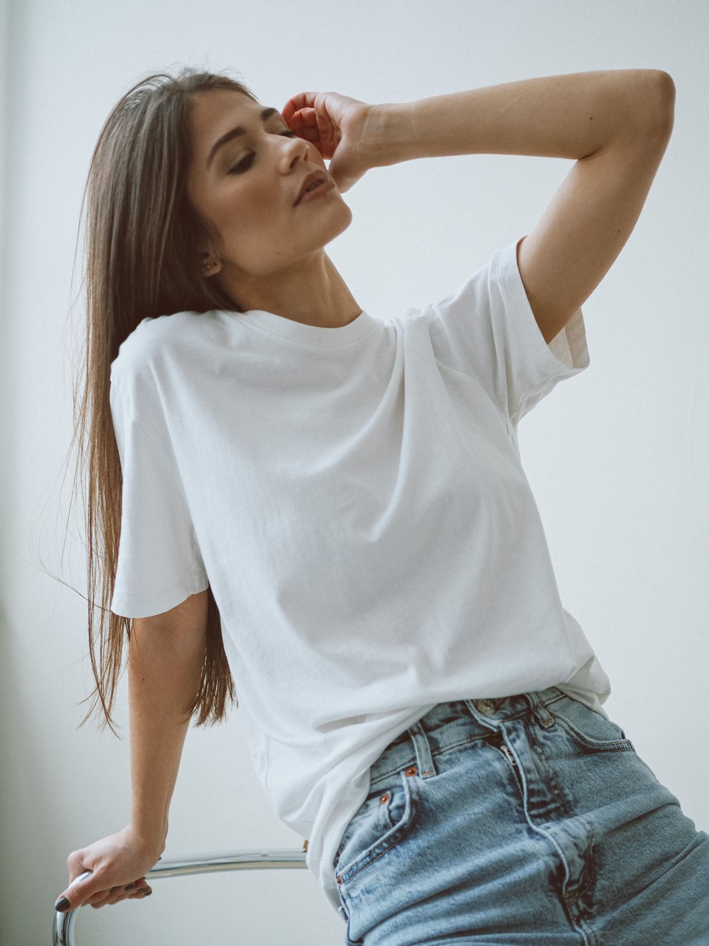 A woman wearing a plain white crew-neck T-shirt with jeans.