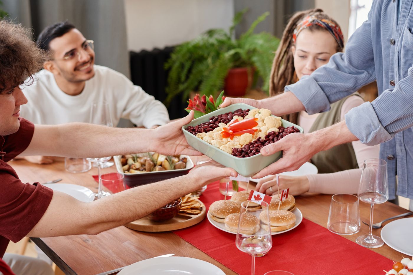 Friends passing a serving dish around a shared meal.