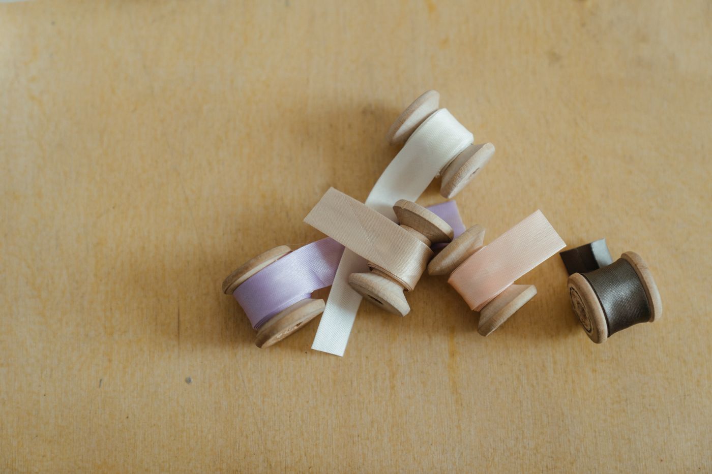 Spools of ribbon kept together on a wooden surface.