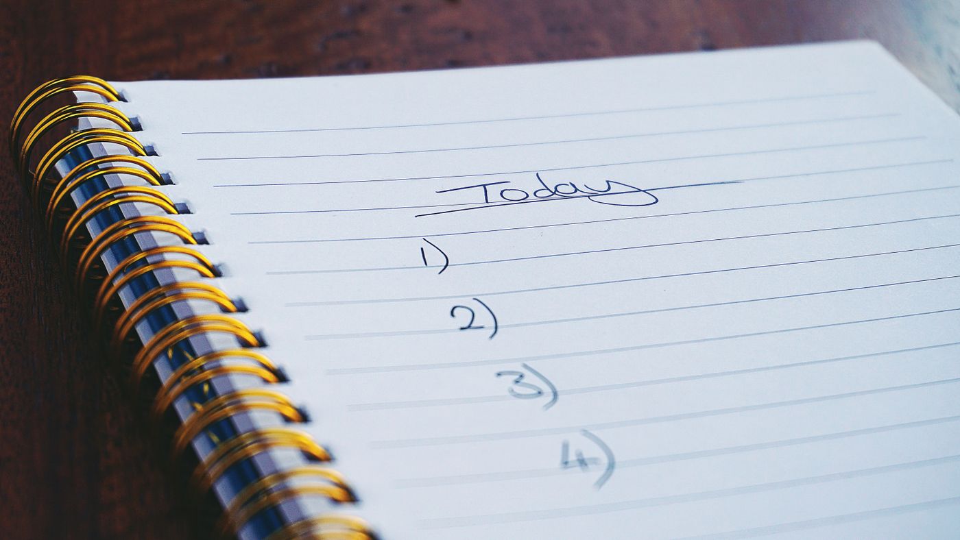 An open spiral notebook with a handwritten task list.