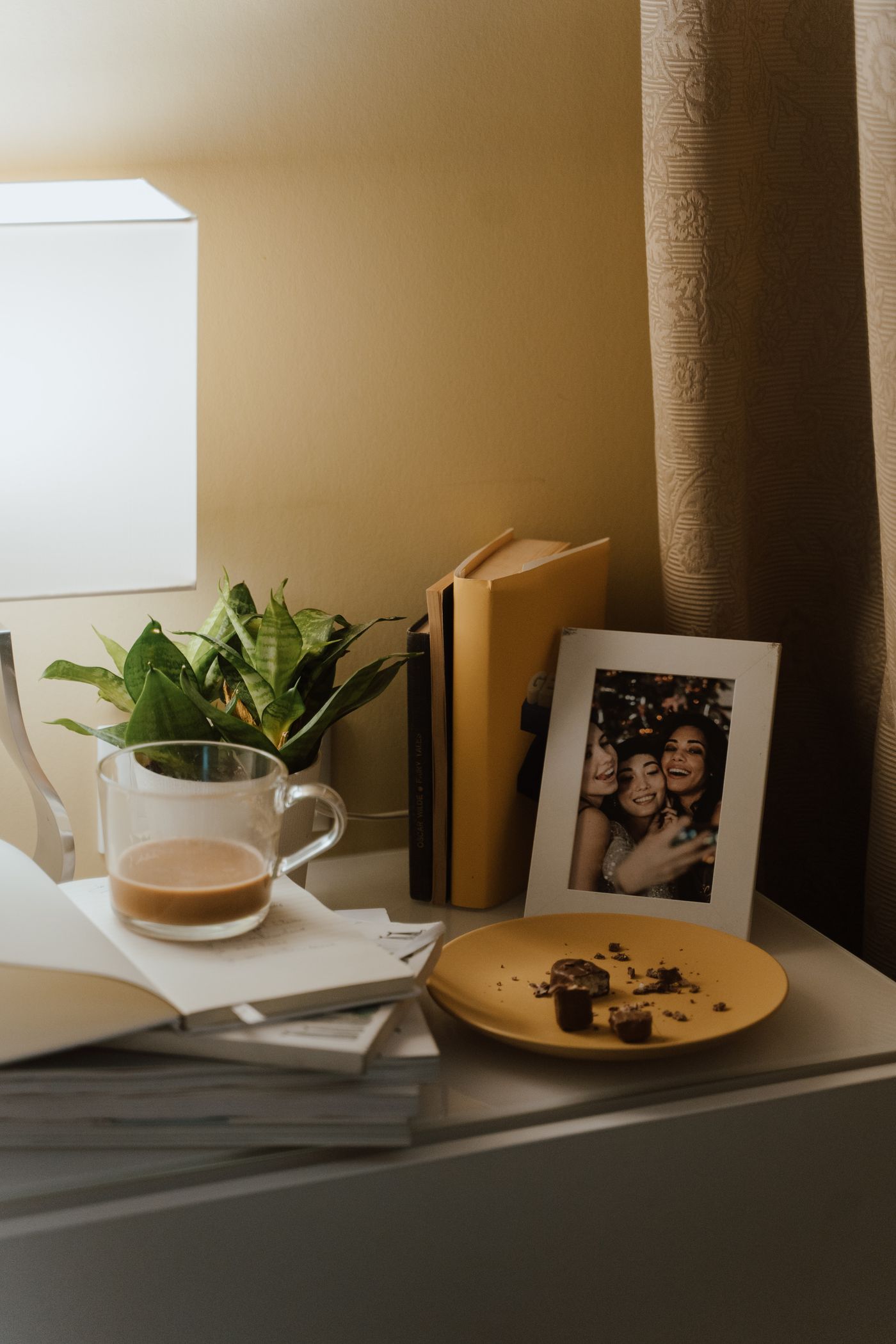 A side table holding a mug, books, a plant and a framed photograph.