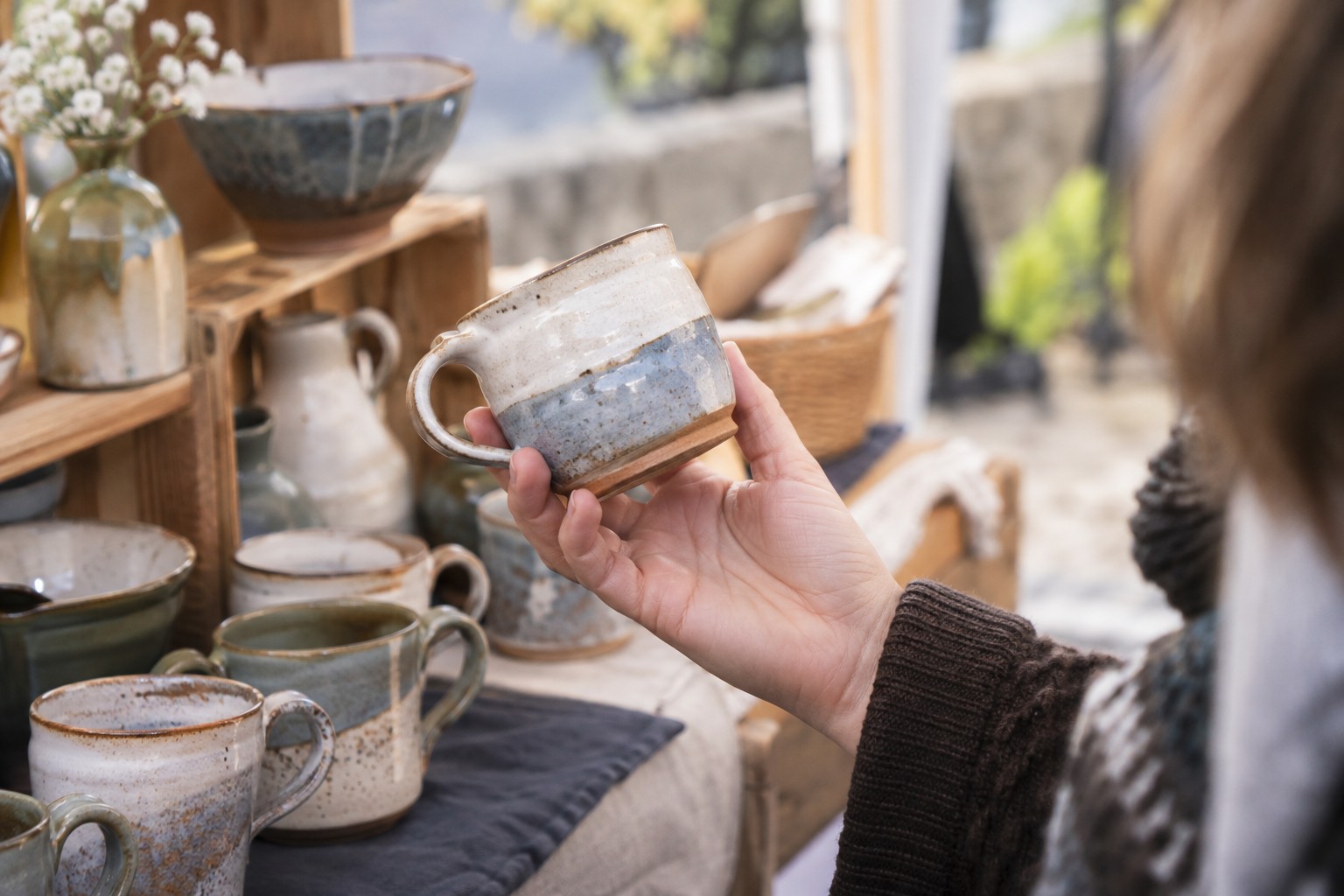 A shopper examining a handmade ceramic mug.