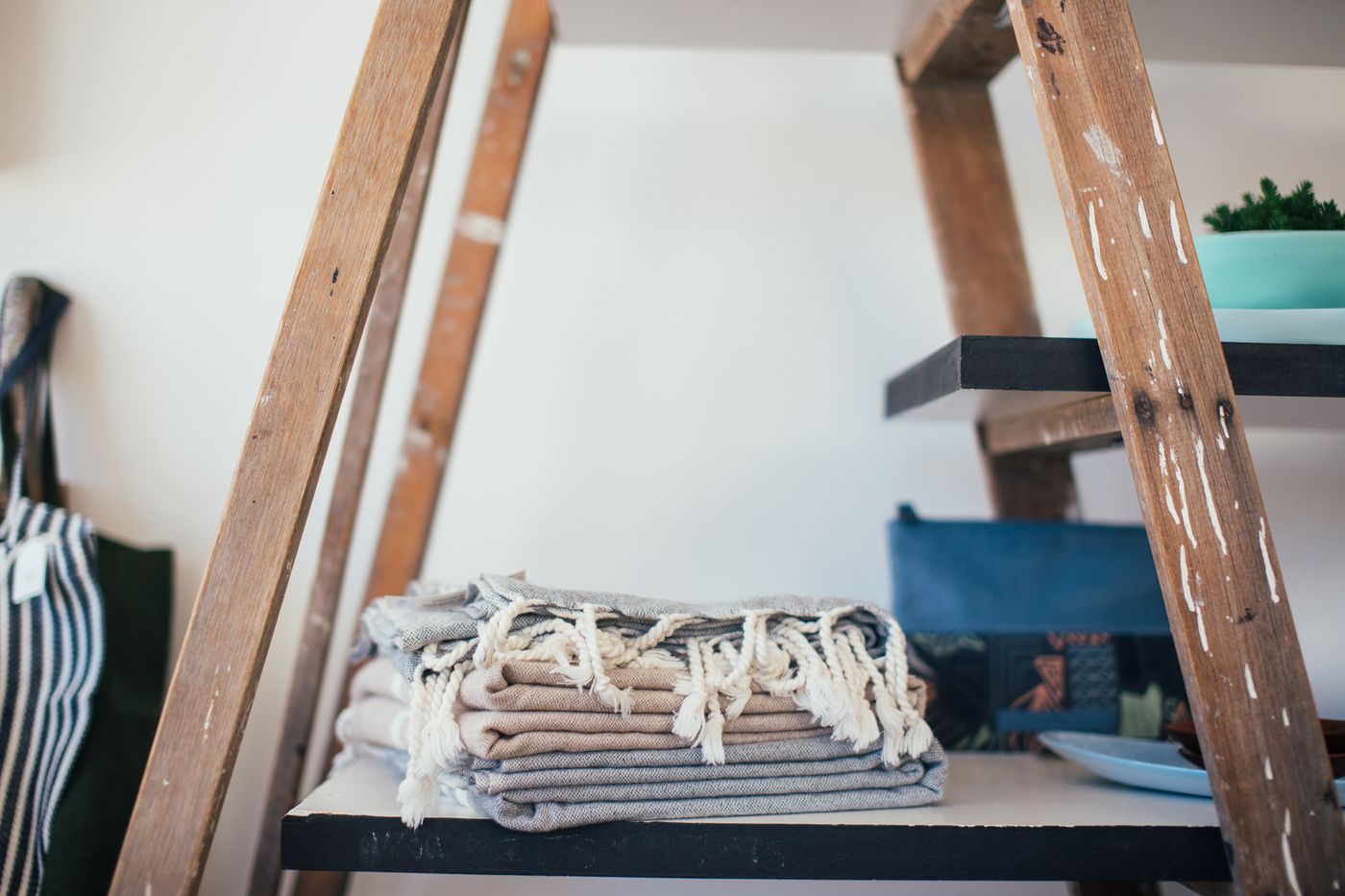 Folded fringed towels on an open storage shelf.
