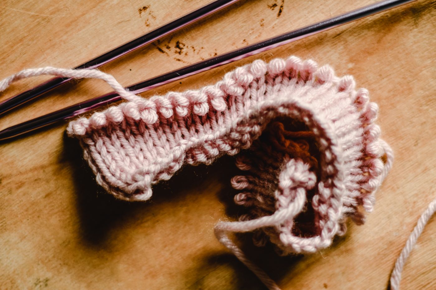 Unfinished pink knitting still on its needles.