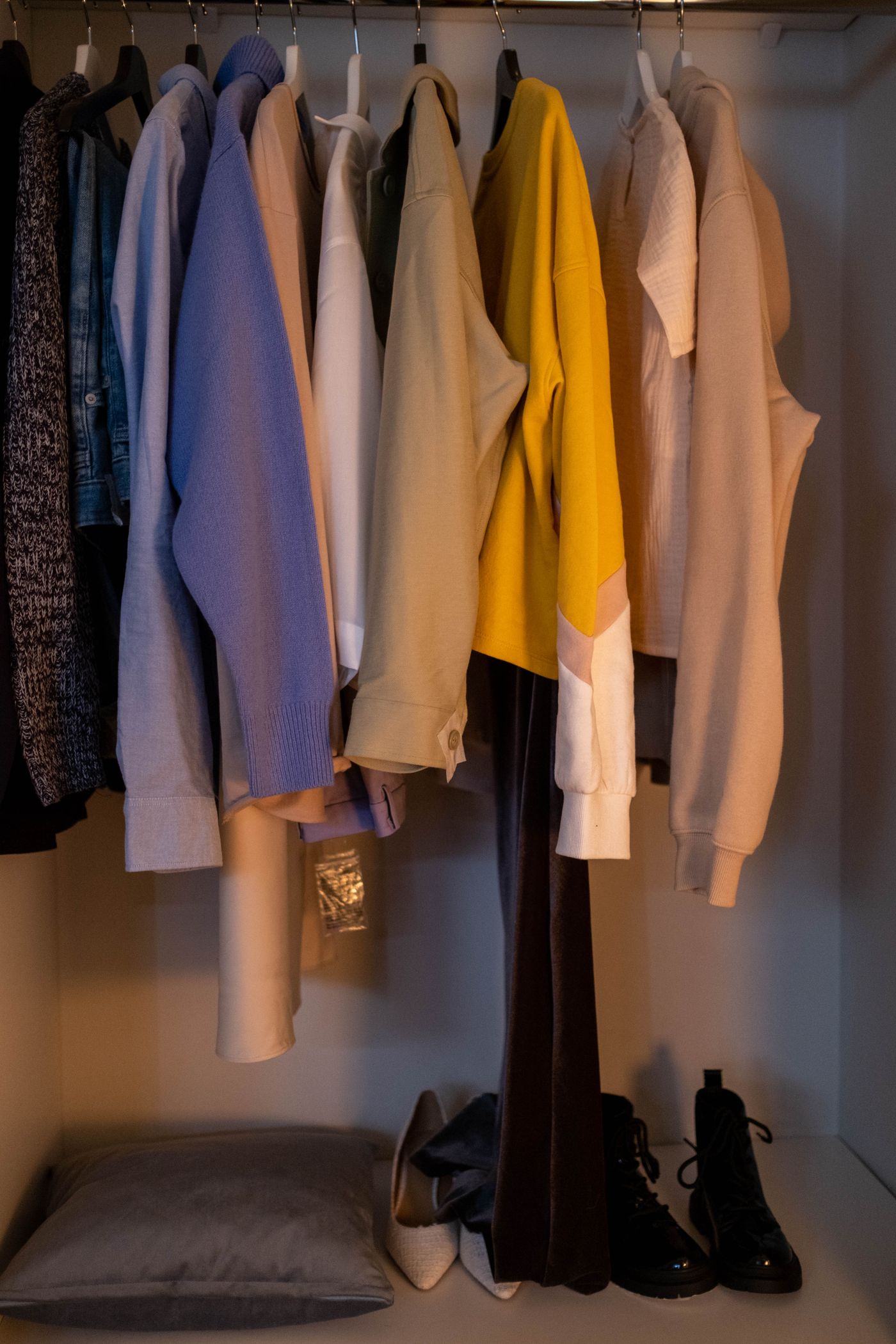 A wardrobe with hanging clothes and shoes arranged below.