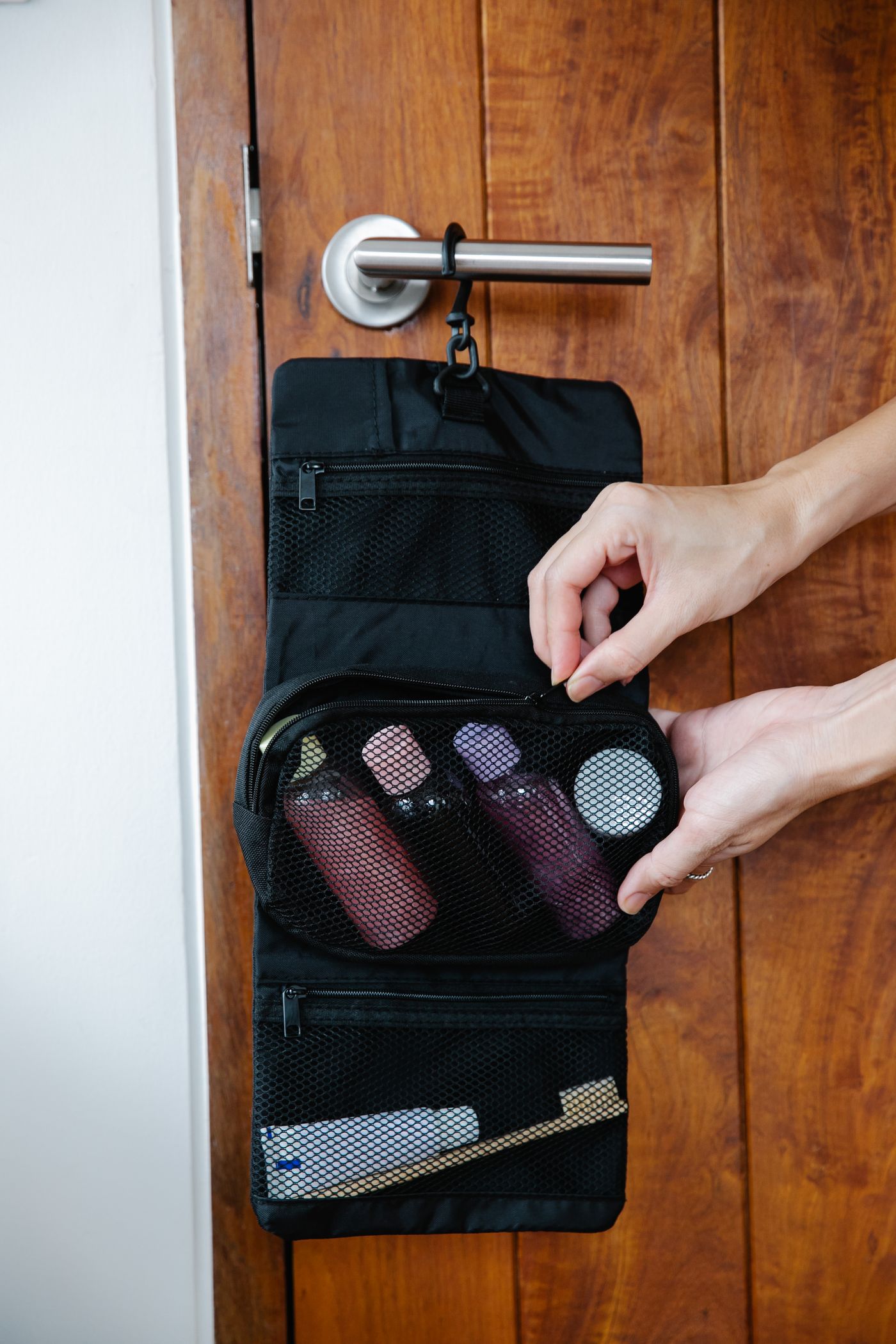An open toiletry pouch hanging from a door handle.