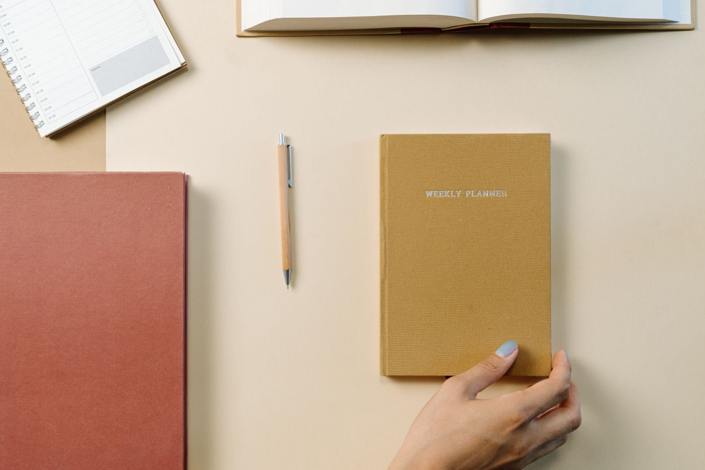 A weekly planner and notebooks arranged on a pale desktop.
