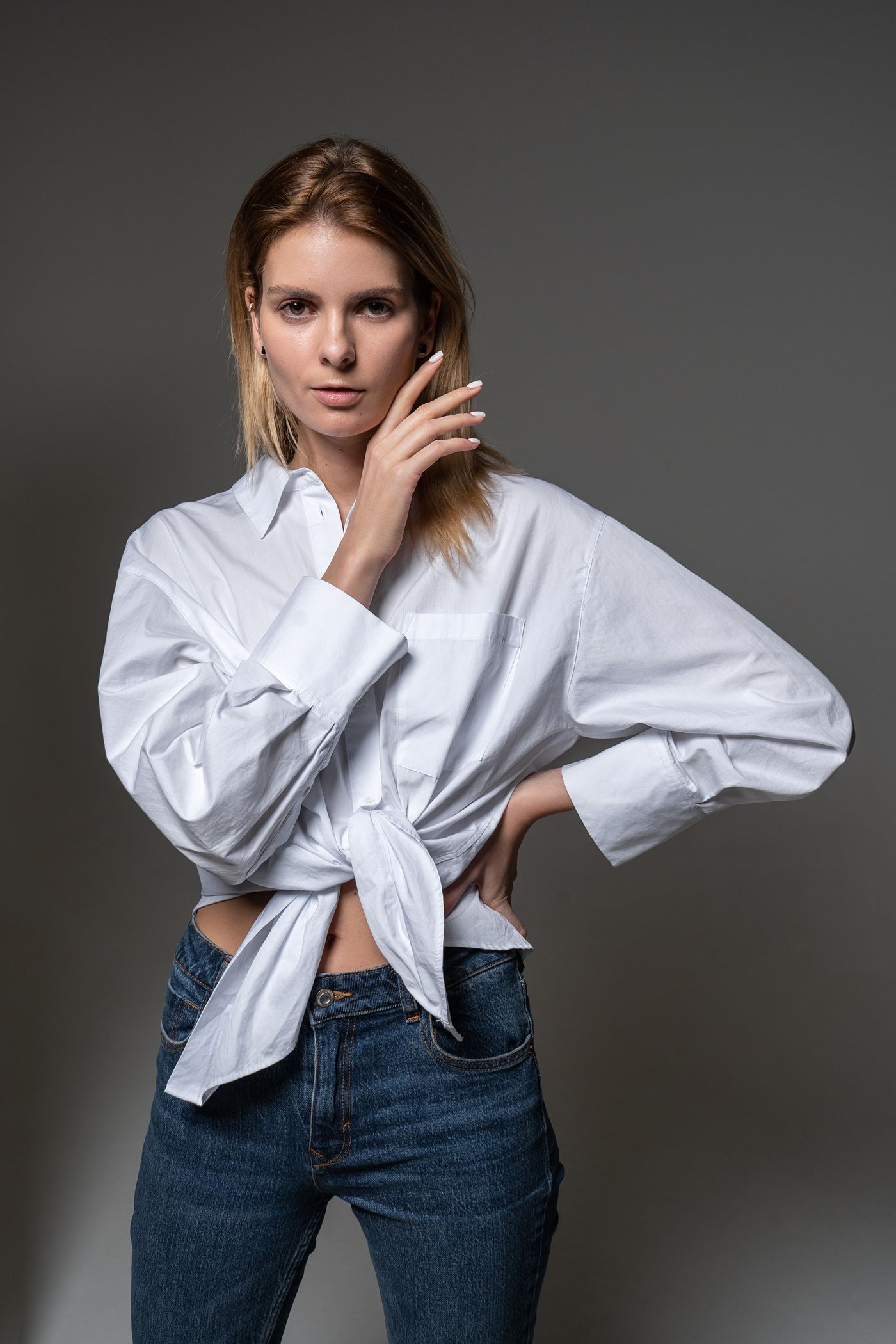 A white button-front shirt tied at the waist and worn with blue jeans.